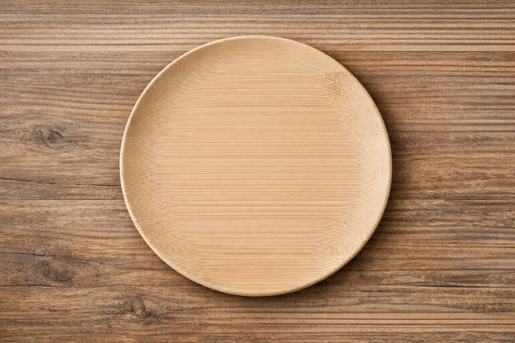 Close-up of a natural bamboo plate showing smooth matte finish and organic grain texture — eco-friendly bamboo tableware made from renewable bamboo fiber
